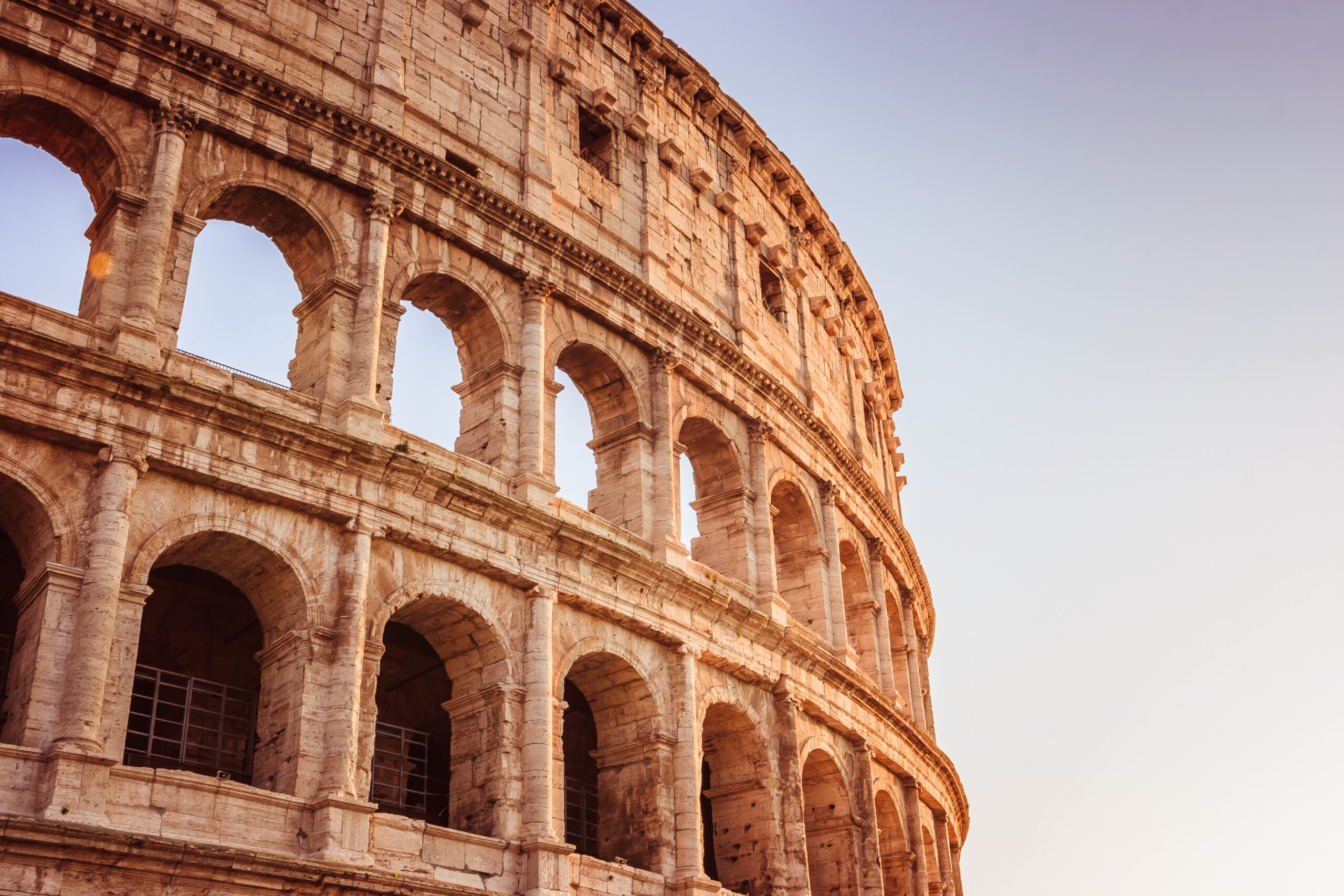Scenic sunset over the Colosseum. Marble arches ruins over a blu